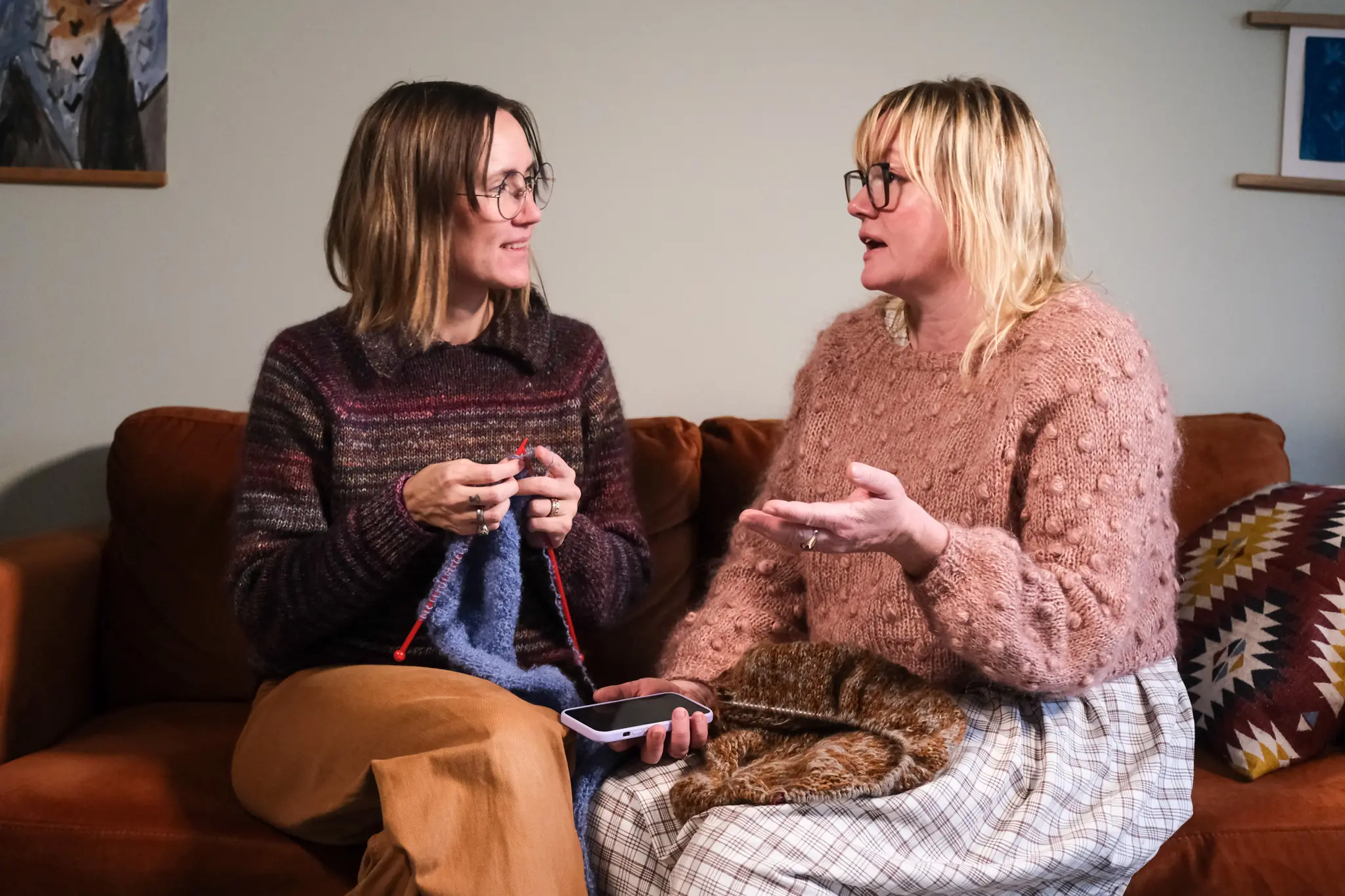 Mette og Helena sidder på en sofa med meget garn
